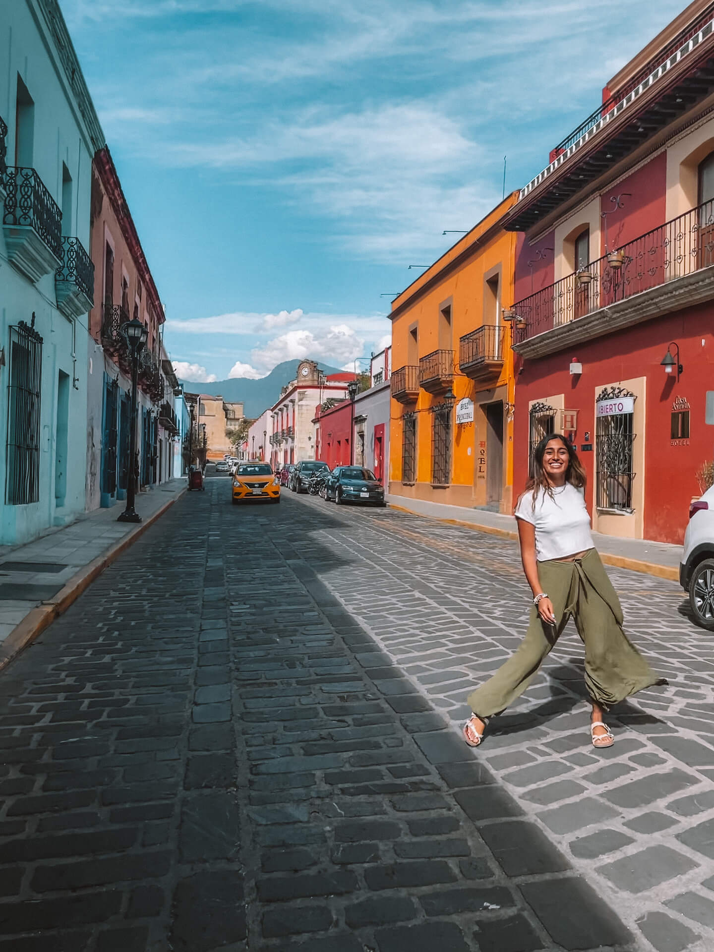 Nabila Ismail poses in the middle of a cobbled street lined with colorful buildings