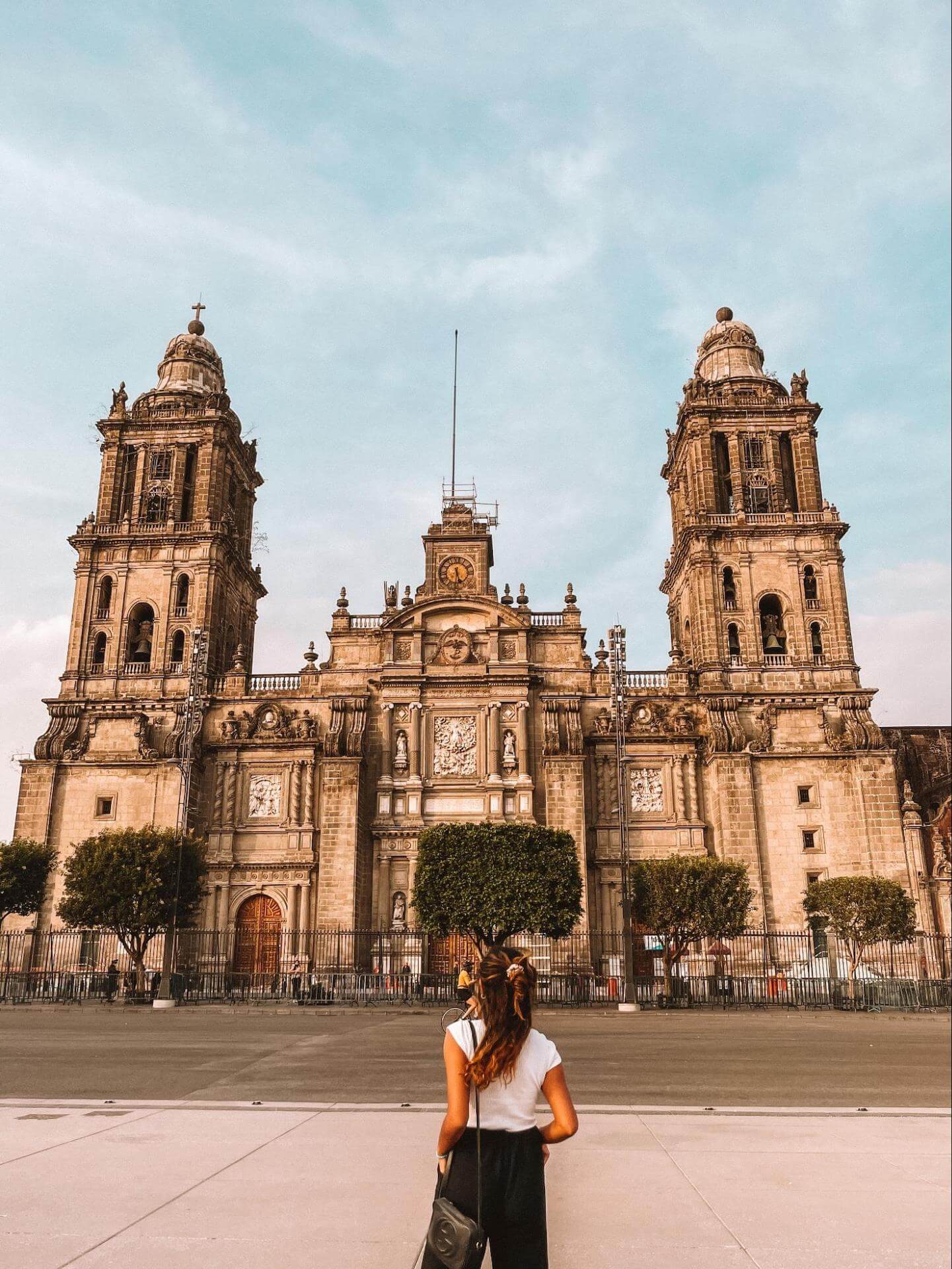 Nabila Ismail of Dose of Travel stands with her back to the camera facing a historic building in Mexico City