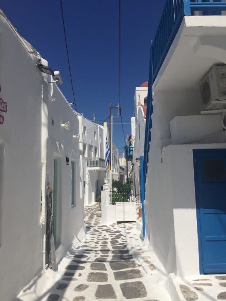Cobble road, white and blue buildings on either side.
