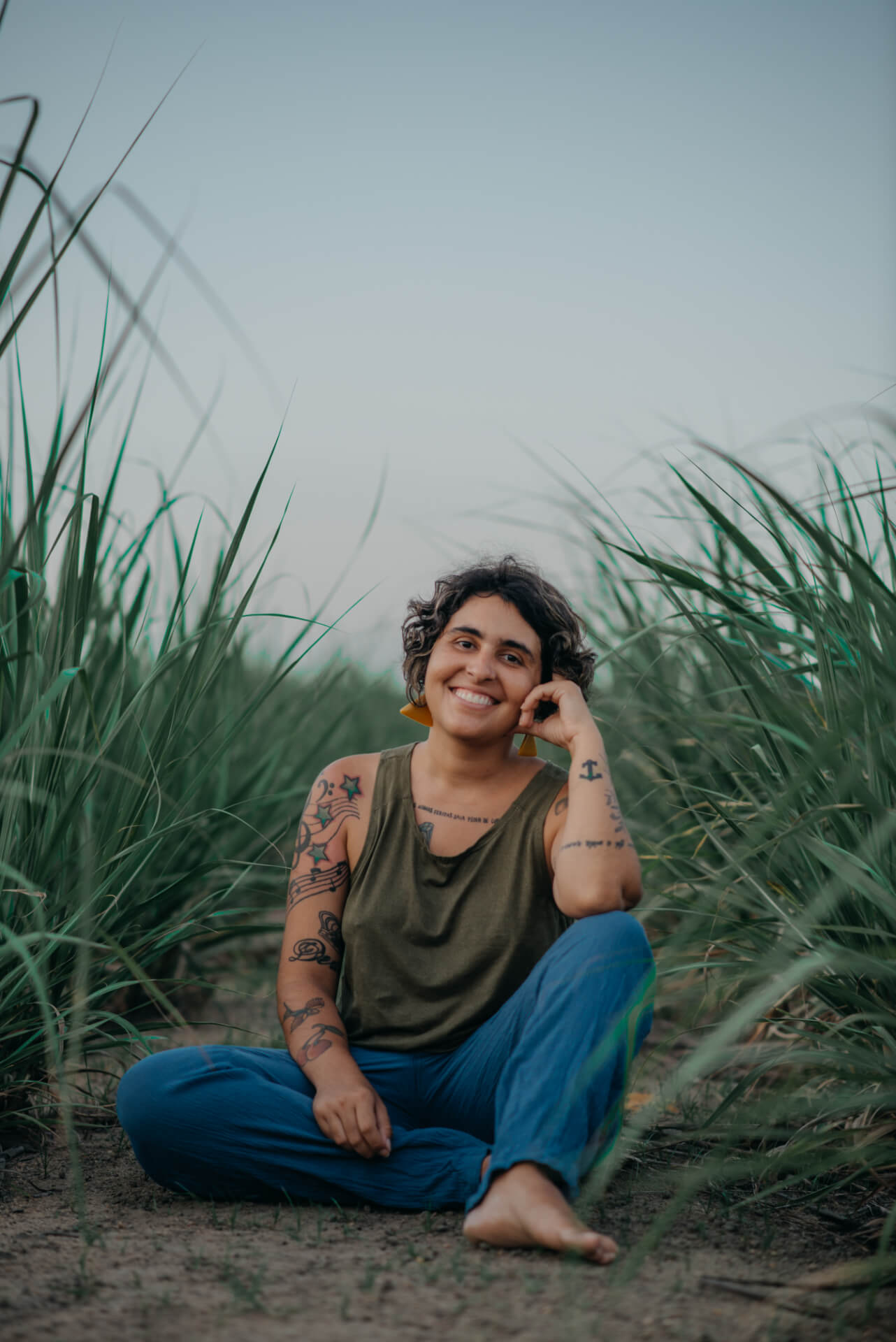 Photographer Céu Albuquerque sitting comfortably on the ground in a green tank top and jeans