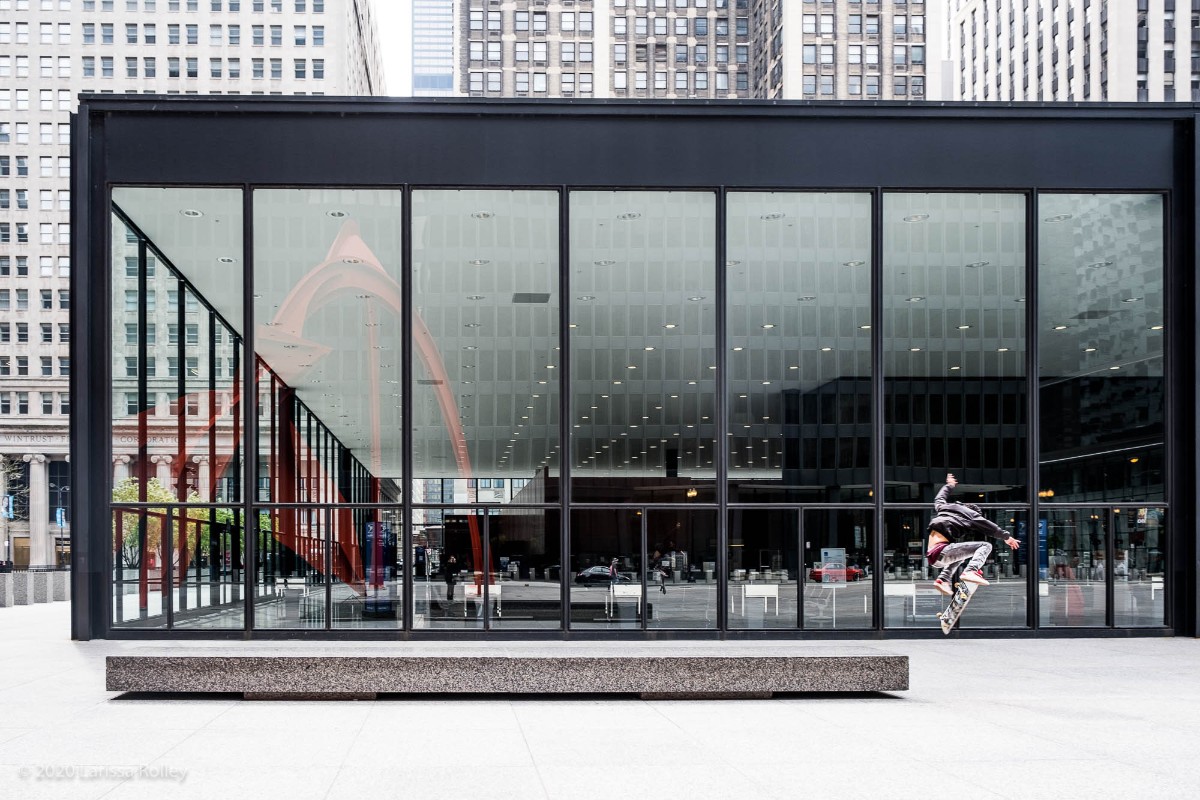 Skateboarder practicing jumps in front of large glass windows in a modern city building - photo by Larissa Rolley, photography course creator at Wanderful