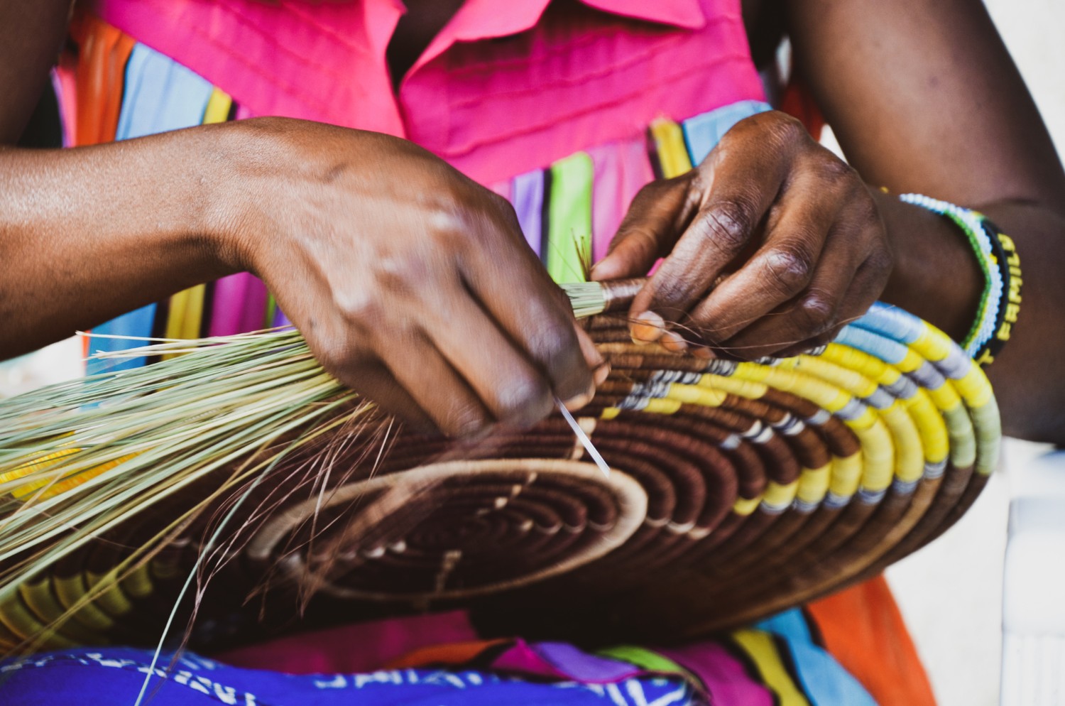 Close-up of a woman\'s hands as she weaves a traditional Rwandan peace basket