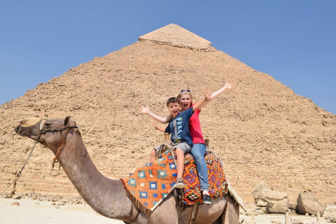 Mom and son on a camel in front of a pyramid