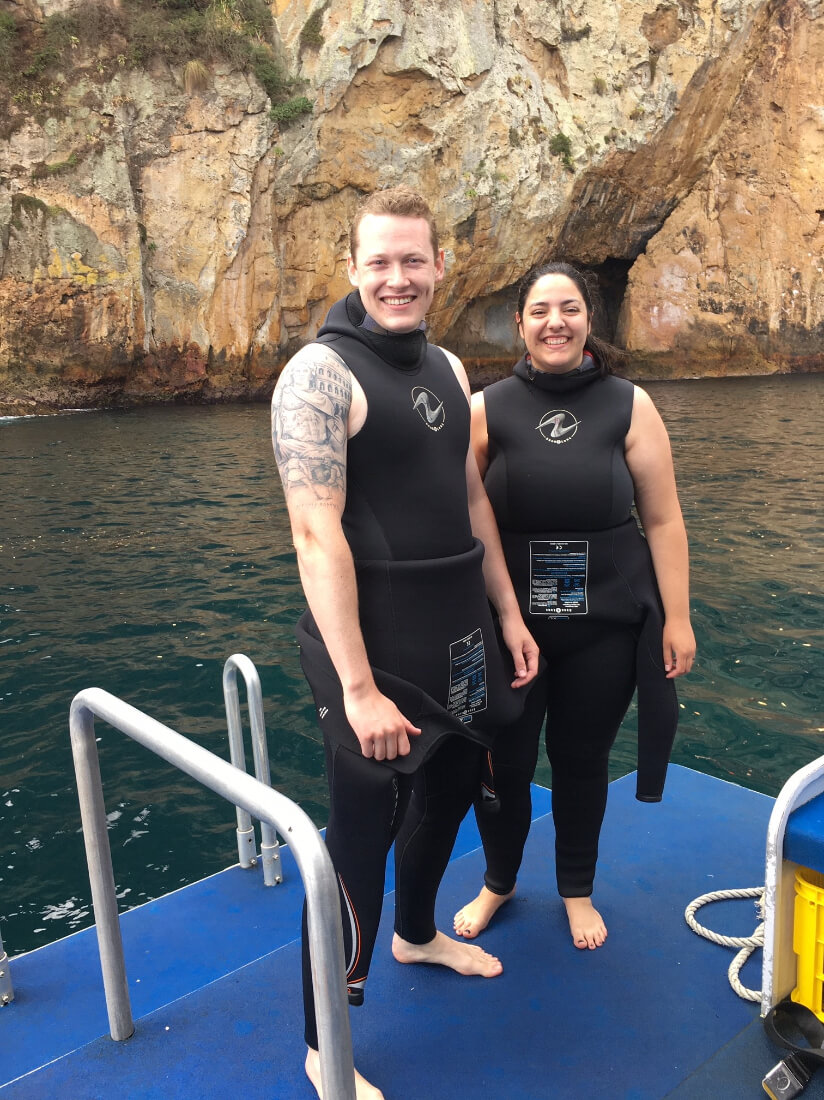 McKenna Hurd and her husband in wetsuits ready for their first ocean scuba diving experience in New Zealand