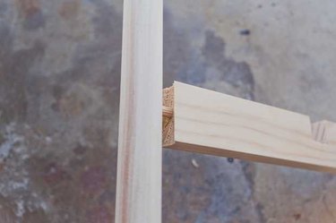 Inserting a dowel into the cross brace, then fitting the cross brace into the hole in the stand