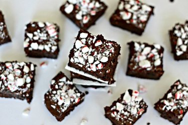 Overhead view of peppermint-topped brownies on a white work surface.