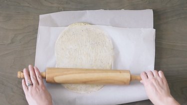 Rolling pizza dough between sheets of parchment paper