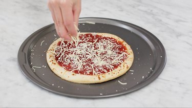 Sprinkling parmesan cheese on pizza crust