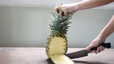 Slicing off pineapple skin