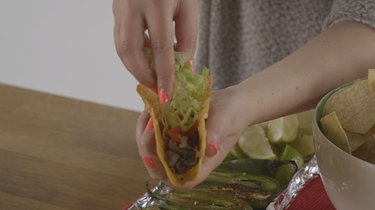 Filling taco with meat, cheese and lettuce.