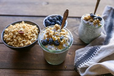 Two jars of chia seed pudding topped with blueberries and granola