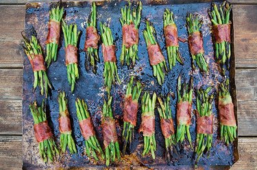Several prosciutto and green bean bundles on a cookie sheet