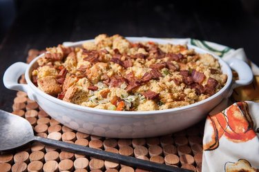 A white casserole dish full of corn bread and bacon stuffing
