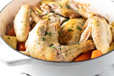 A dutch oven full of roasted chicken, potatoes and carrots