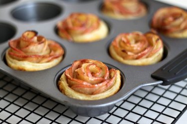 A muffin tin full of floral apple mini pies