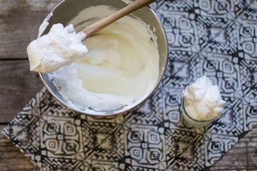 A mixing bowl full of homemade whipped cream on a table runner