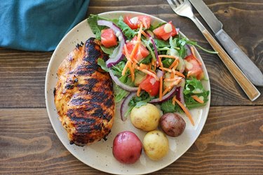 Grilled chicken on a plate with salad and potatoes