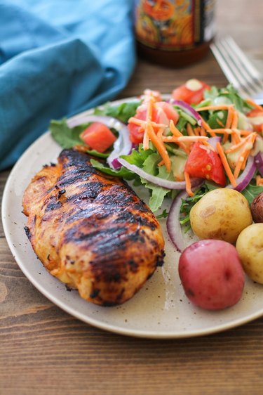 Grilled chicken on  a plate with potatoes and salad