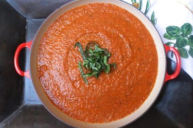 A large pot of tomato sauce with chopped basil.