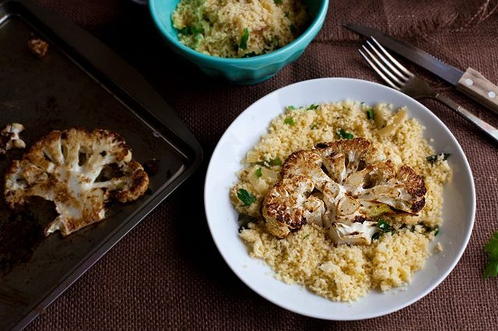 Roasted and browned cauliflower steaks on a bed of caramelized onion couscous.