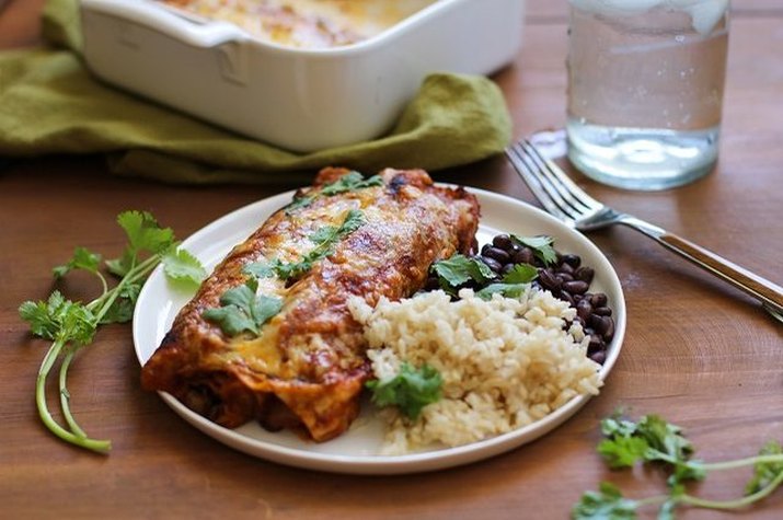 A vegetarian enchilada served with black beans and rice.