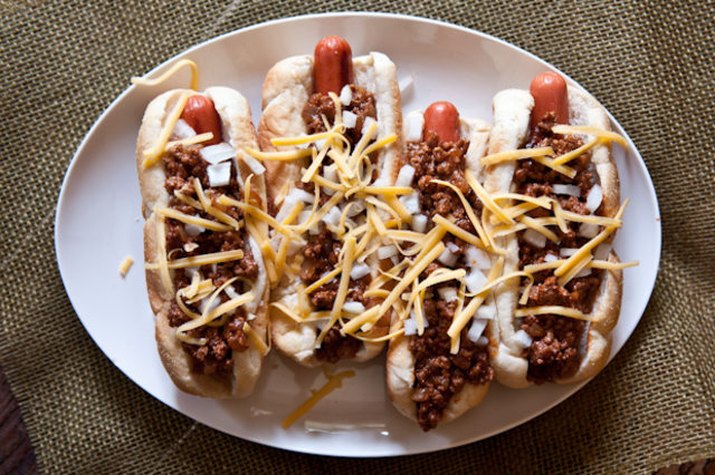 Four chipotle stout chili dogs sprinkled with shredded cheese.
